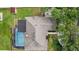Aerial view of home featuring a screened-in pool, patio, lush landscaping, and well-maintained roof at 1922 Matthew Ct, Lakeland, FL 33813