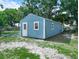 A bright blue shed with white trim sits on a grassy lot with trees in the background at 2120 Dille St, Lakeland, FL 33815
