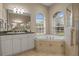 Bright bathroom with tub, walk-in shower, and large vanity, featuring a neutral color palette and tile flooring at 2593 Colonel Ford Dr, Lakeland, FL 33813