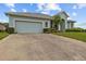 Spacious driveway leads to a home with a light blue exterior, accented by lush landscaping and an attached garage at 2593 Colonel Ford Dr, Lakeland, FL 33813