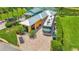 Aerial view of a charming yellow home with a paved driveway and a large RV parked alongside it at 3261 Fish Hawk Dr, Polk City, FL 33868