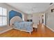 Bright bedroom features wood floors, ceiling fan, and a blue accent wall with decorative metal art at 3487 Highland Fairways Blvd, Lakeland, FL 33810
