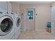Laundry room with washer, dryer, tile floors, access door, and storage at 3487 Highland Fairways Blvd, Lakeland, FL 33810
