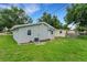Backyard view featuring a well maintained lawn, home, trees, blue skies, and landscaping at 3601 Avenue R Nw, Winter Haven, FL 33881