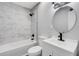 Bathroom featuring modern vanity, round mirror, shower over tub and marble look tile at 3601 Avenue R Nw, Winter Haven, FL 33881