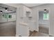 View of the kitchen with its white cabinetry, connecting seamlessly to the spacious, well-lit living area at 3601 Avenue R Nw, Winter Haven, FL 33881
