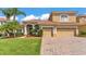 Charming tan two-story home with a brick driveway, lush lawn, and well-maintained landscaping at 3980 Sunset Lake Dr, Lakeland, FL 33810