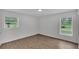 Bright bedroom with light wood floors, two large windows, and freshly painted white walls at 408 Sycamore Sw St, Fort Meade, FL 33841