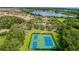 Aerial view of tennis and basketball courts surrounded by trees and near a lake in a community at 4125 Prima Lago Cir, Lakeland, FL 33810