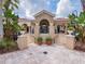 Elegant clubhouse entrance with stone accents, tiled roof, and lush tropical landscaping at 4125 Prima Lago Cir, Lakeland, FL 33810
