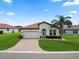 Inviting single-Gathering home featuring a tiled roof, a two-car garage, and lush landscaping at 4125 Prima Lago Cir, Lakeland, FL 33810
