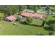 Aerial view of property with red metal roof, mature trees, and partially fenced in area at 5140 Alderman Rd, Lakeland, FL 33810
