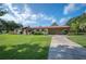 Single story home with a red metal roof, a long driveway, and a well-manicured lawn at 5140 Alderman Rd, Lakeland, FL 33810