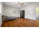 Bright bedroom showcasing wood floors, a window, ceiling fan, a wardrobe, and easy access to the ensuite bathroom at 545 Prado Pl, Lakeland, FL 33803