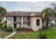 Multi-level building with a stone balcony feature, tropical landscaping, and well-maintained grounds at 803 Orchid Springs Dr, Winter Haven, FL 33884