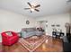 Cozy living room with wood floors, ceiling fan, sectional sofa, and view into possible sunroom at 803 Orchid Springs Dr, Winter Haven, FL 33884
