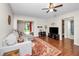 Open concept living room boasts wood flooring, ceiling fan, gray sofa, and view into bath and sunroom at 803 Orchid Springs Dr, Winter Haven, FL 33884