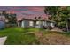 Exterior view of a gray one-story home with a paver patio and green lawn during sunset at 1020 E Palmetto St, Lakeland, FL 33801