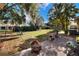 A spacious backyard featuring a brick patio, fire pit, lush lawn, and playground equipment at 1118 Cypress W Pt, Winter Haven, FL 33884