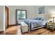 Bedroom features white metal bed frame, light blue comforter, wood floors, natural light, and white walls at 1118 Cypress W Pt, Winter Haven, FL 33884