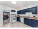 Well-lit kitchen featuring blue cabinets, white appliances, and a view into the living room at 1125 Josephine St, Lakeland, FL 33815
