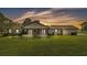 Beautiful manicured backyard with green lawn and an exterior view of the home at sunset at 118 Caloosa Dr, Babson Park, FL 33827