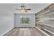 Modern bedroom with wood accent wall, bay window, ceiling fan, and plank floors at 118 Caloosa Dr, Babson Park, FL 33827