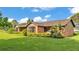 Side view of home featuring a brick facade, manicured landscaping, and lush green lawn at 118 Caloosa Dr, Babson Park, FL 33827