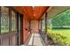 Covered front porch with stylish wood accents, brick siding, and manicured shrubbery at 118 Caloosa Dr, Babson Park, FL 33827