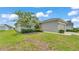 Home exterior view featuring a well-manicured lawn, flowering tree, and an attached garage at 122 St Thomas Dr, Mulberry, FL 33860
