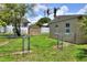 Backyard with a shed, two storage buildings, a fenced-in area, lush green grass, and sunny skies at 124 Carolyn Dr, Lakeland, FL 33803