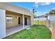 A backyard with a covered porch, featuring two exterior doors, a grassy area, and a chain-link fence surrounding the perimeter at 124 Carolyn Dr, Lakeland, FL 33803