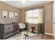 Bedroom with a gray crib, chair, and window with a patterned rug at 124 Carolyn Dr, Lakeland, FL 33803
