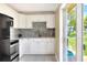 Bright kitchen features white cabinets, tiled backsplash, stainless appliances, and sliding glass door at 124 Carolyn Dr, Lakeland, FL 33803