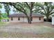 Home's rear exterior with a white door, windows and a large tree providing shade at 1300 Ariana Woods Cir, Auburndale, FL 33823
