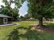 Spacious backyard with healthy lawn, mature trees, and storage shed creates the perfect serene outdoor space at 1315 Costine Dr, Lakeland, FL 33809