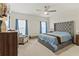 Bright bedroom featuring a tufted headboard, neutral carpeting, and natural light from two large windows at 1371 Madison Cir, Haines City, FL 33844