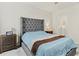 This bedroom showcases a gray tufted headboard, a nightstand, and a doorway to an ensuite bathroom at 1371 Madison Cir, Haines City, FL 33844