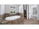 Elegant bathroom with a soaking tub, tiled shower, and plantation shutters at 1739 Laurel Glen Pl, Lakeland, FL 33803