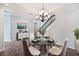 Open dining area features a modern chandelier, glass table, and decorative staircase for an inviting ambiance at 1739 Laurel Glen Pl, Lakeland, FL 33803