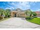 Charming home featuring a two-car garage, a well-manicured lawn, and lush landscaping with palm trees at 1739 Laurel Glen Pl, Lakeland, FL 33803