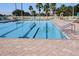 Community swimming pool with marked lanes, ladder, brick trim, white fence, and lounge chairs in the background at 1739 Laurel Glen Pl, Lakeland, FL 33803