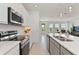 White kitchen with stainless steel appliances that opens into a living area with access to the backyard at 1754 Sanibel Dr, Davenport, FL 33896