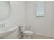 Clean powder room with a pedestal sink, toilet, round mirror and window at 1754 Sanibel Dr, Davenport, FL 33896