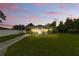 Charming single-story home featuring a well-maintained lawn and mature landscaping during a colorful sunset at 1820 Salem Rd, Lakeland, FL 33803