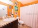 Bright bathroom with orange walls, shower curtain, single vanity, and tiled floors at 1824 Baltic Pl, Lakeland, FL 33809