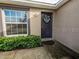 Front entrance featuring a decorated dark-colored door and a vibrant green bush at 1824 Baltic Pl, Lakeland, FL 33809
