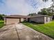 Single-story home with a paved driveway, two-car garage and large, grassy yard at 1824 Baltic Pl, Lakeland, FL 33809