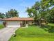 Charming one-story home featuring a well-manicured lawn, mature tree, and attached two-car garage at 1917 Lori W Ln, Lakeland, FL 33801