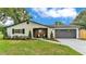 Charming single-story home with a gray roof, wood accents, a long driveway, and green grass at 1920 Kimball S Ct, Lakeland, FL 33813